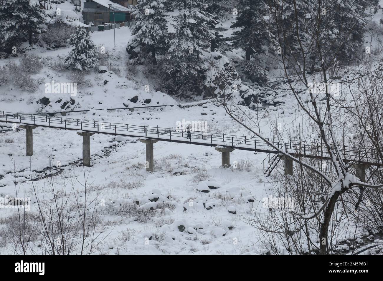December 30, 2022, Srinagar, Jammu and Kashmir, India: Villagers walks on snow covered bridge after fresh snowfall in Tangmarg, some 40 kilimeters north of Srinagar, the summer capital of Indian Kashmir. Higher reaches of Kashmir experienced light to moderate snowfall and light rain lash plains. The spell has broken cycle of intense cold wave in the region. (Credit Image: © Sajad Hameed/Pacific Press via ZUMA Press Wire) Stock Photo
