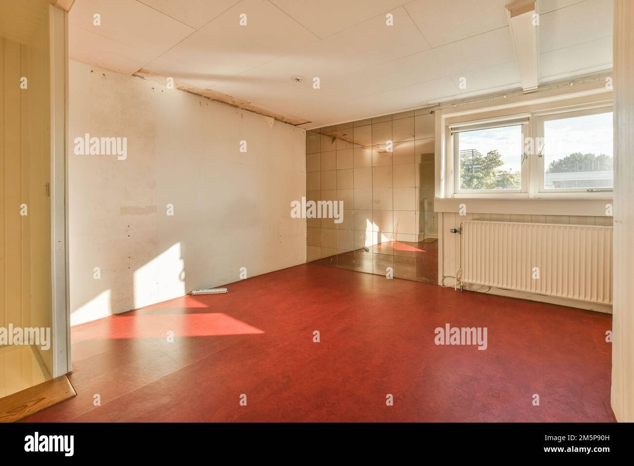 an empty room with red flooring and white walls in the room is being ...