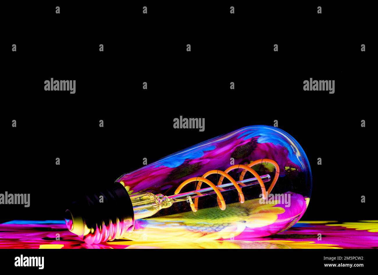 Colourful patterns reflect within a clear glass, oval shaped lightbulb