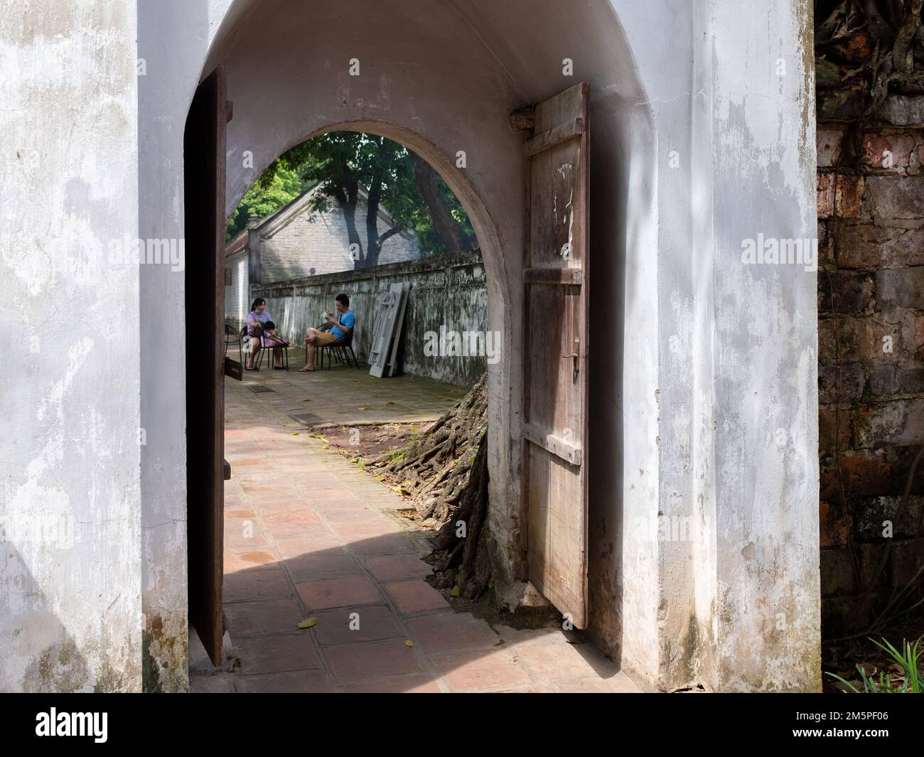Hanoi, Vietnam - June 5, 2022: A couple chatting is seen through a gate Stock Photo
