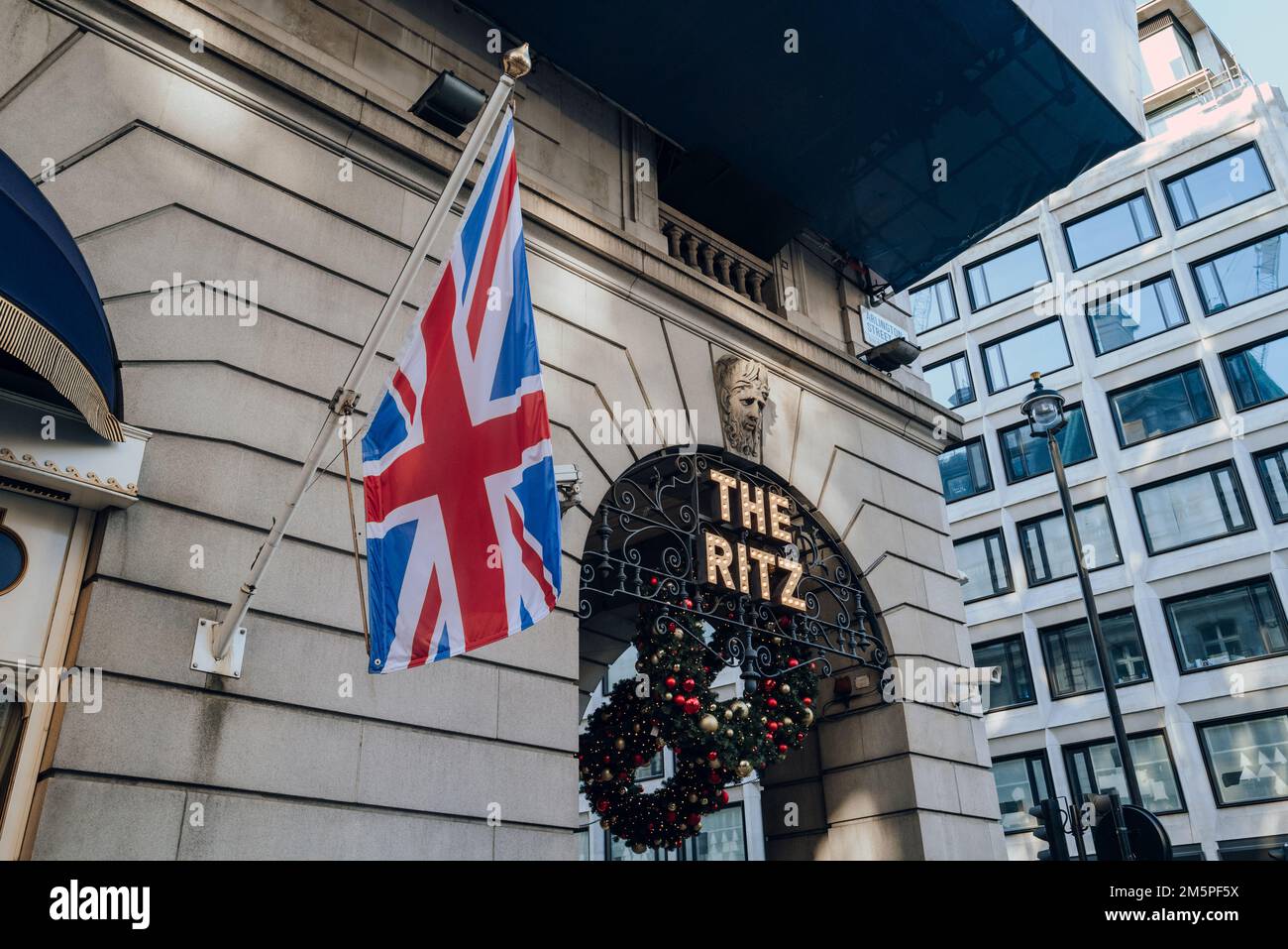 London, UK - December 26, 2022: Sign outside The Ritz, London's most iconic hotel, next to the Union Jack flag on a pole. Stock Photo