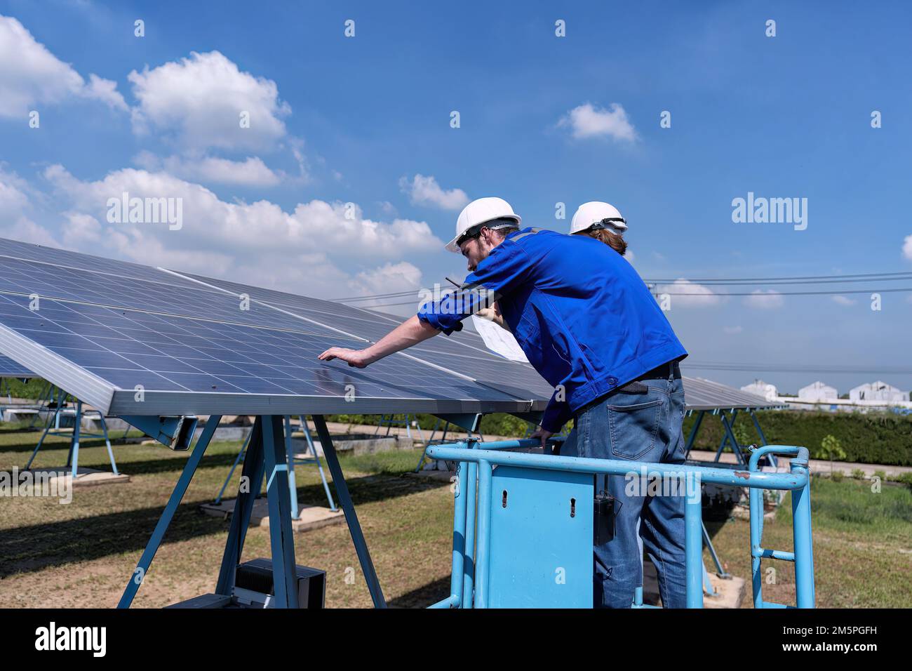 Maintenance engineer at solar farm stand on scissor lift routine inspection solar panel condition Stock Photo