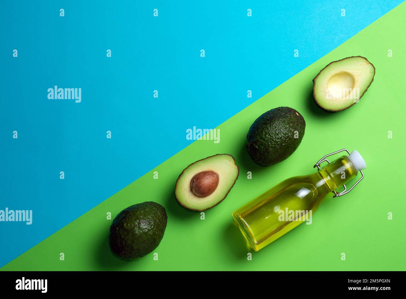 Fresh avocados on a blue and green background. Avocado oil in a bottle. Healthy Eating Stock