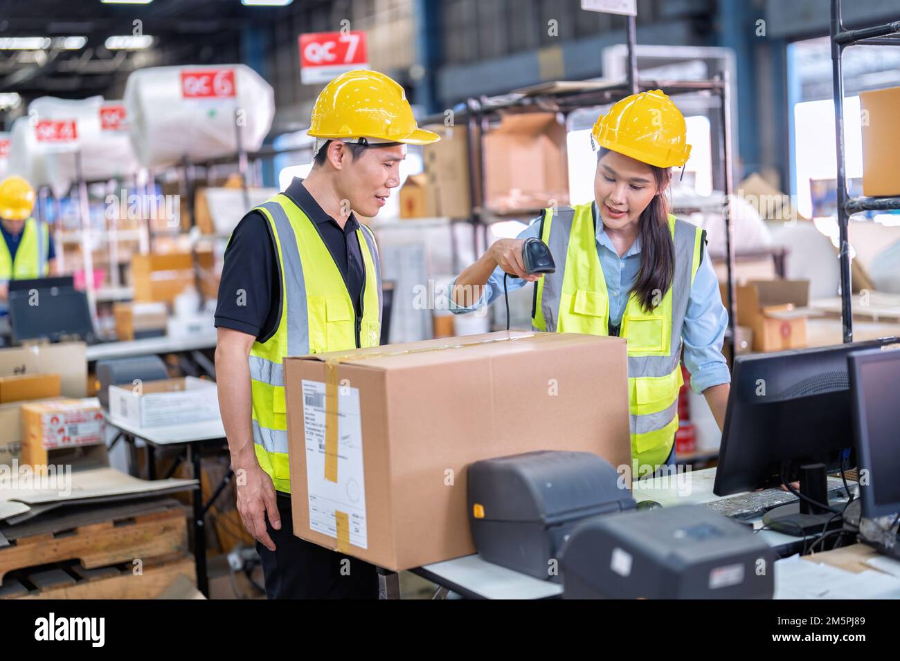 2 Staff working in large depot storage warehouse check packing box and
