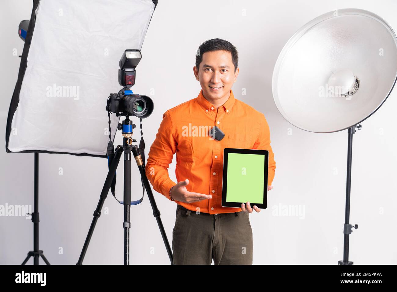 vlogger standing with hand pointing at screen while holding tablet Stock Photo