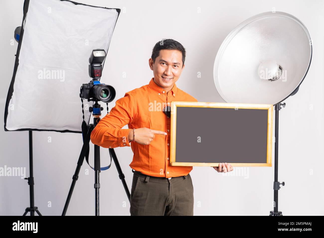 vlogger standing with pointing hand while holding blackboard with lighting Stock Photo