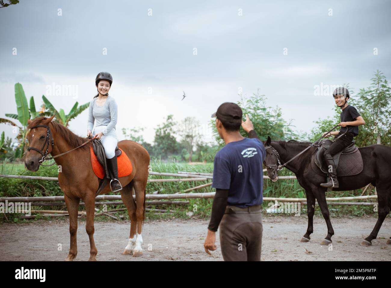 two equestrian athletes riding horses listening to trainer standing guide Stock Photo