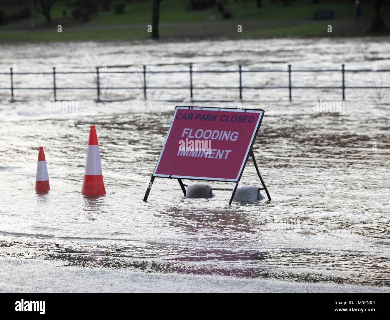 A flood warning sign at the entrance to a flooded car park in