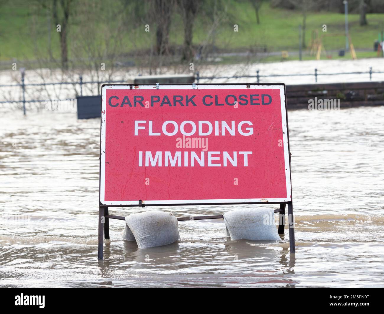 A flood warning sign at the entrance to a flooded car park in