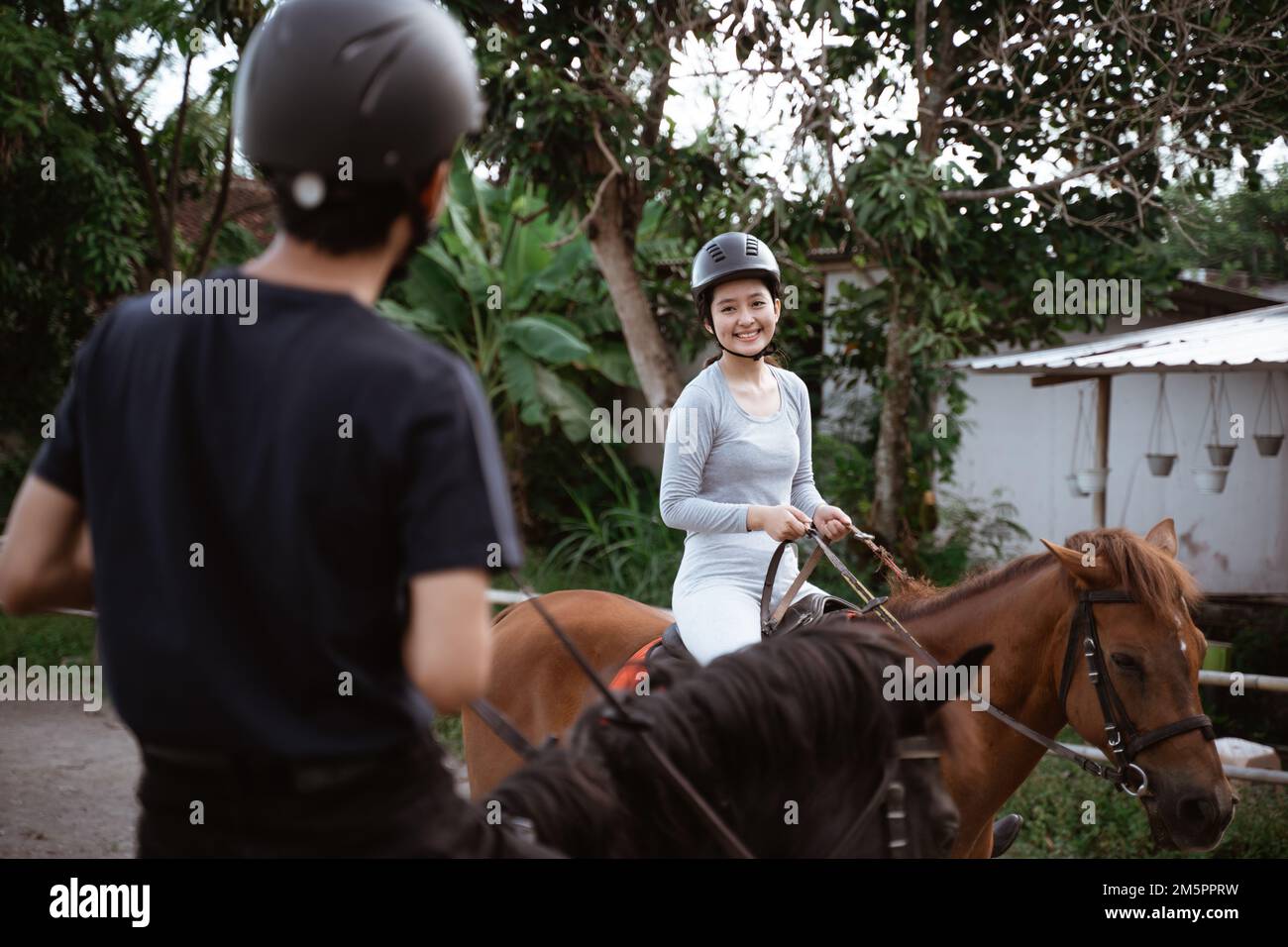 asian female equestrian meets her friend during training Stock Photo