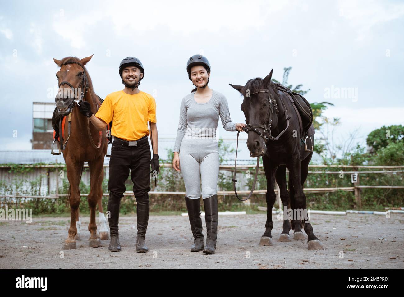 Two equestrian athletes wearing gear standing next to their horses Stock Photo
