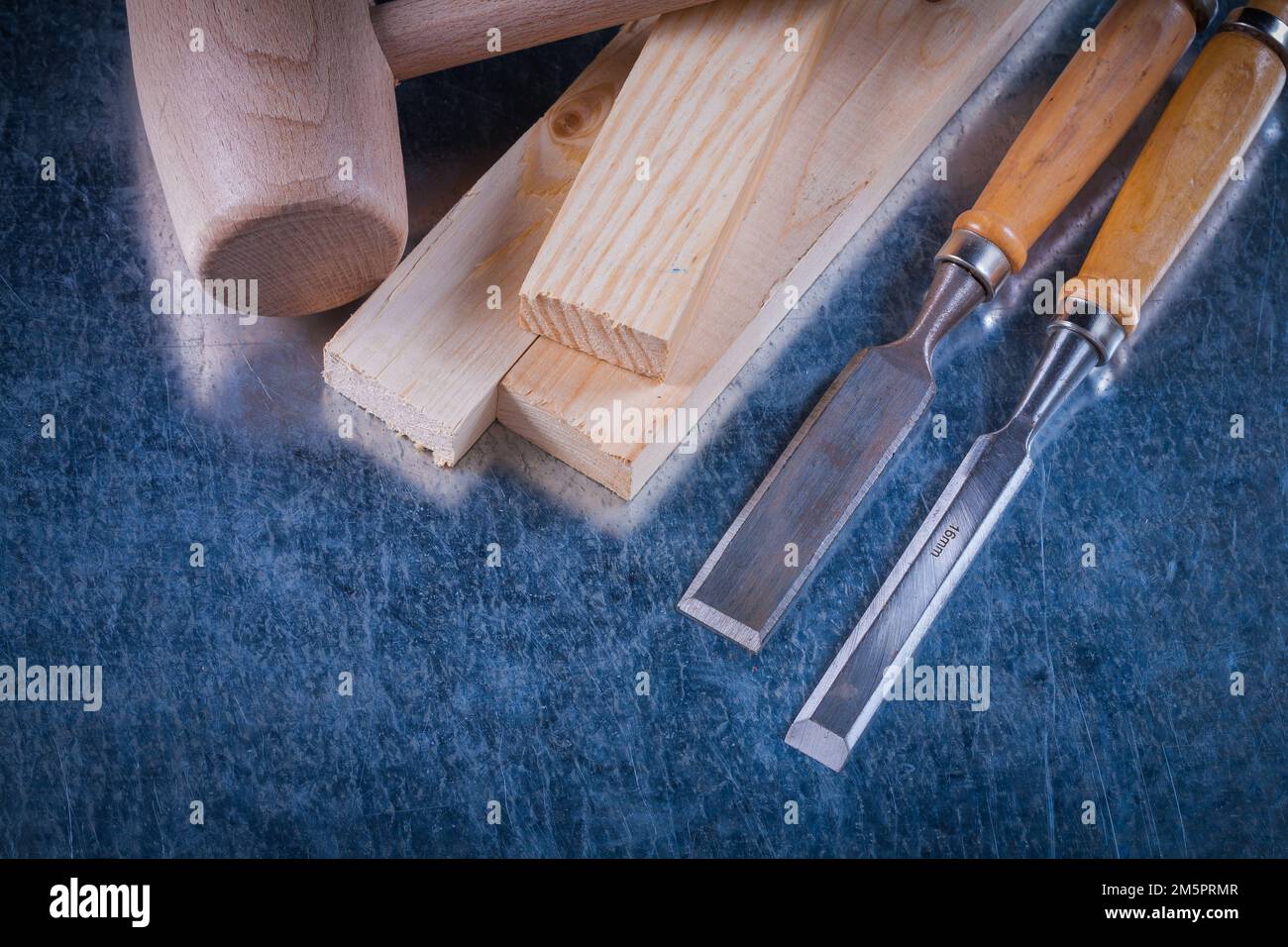 Lump hammer wooden bricks and flat chisels on scratched metallic surface construction concept. Stock Photo