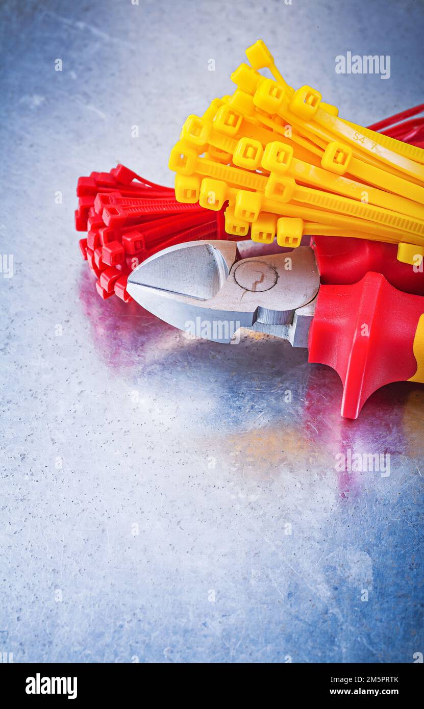 Nippers tying cables on scratched metallic background. Stock Photo