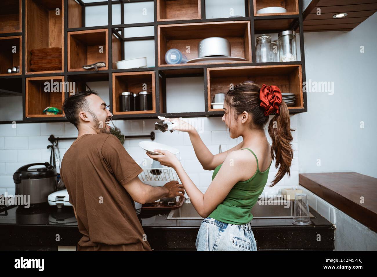 rear view of boy and girl joking while washing dishes Stock Photo
