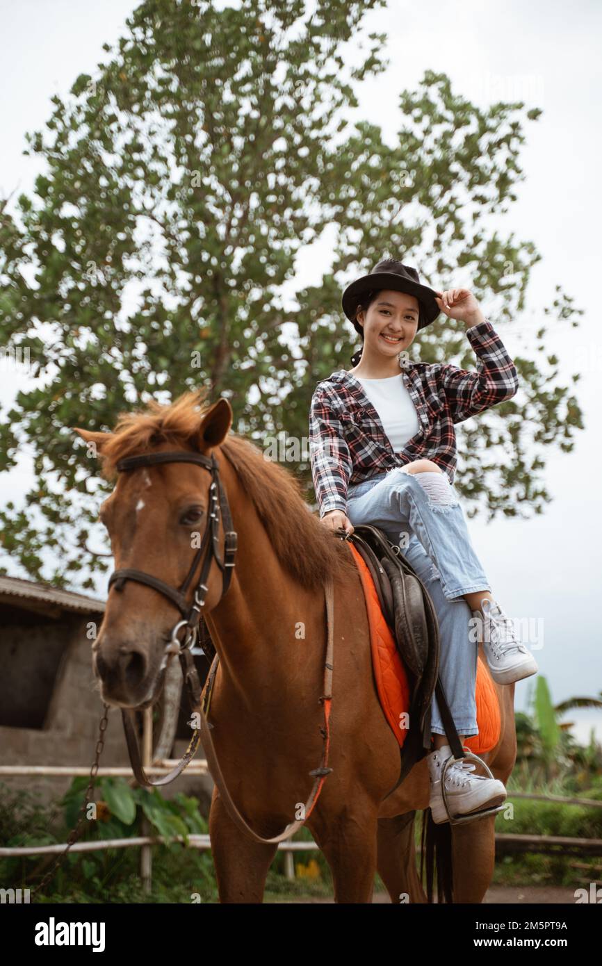 beautiful cowboy girl smiling sitting on horse on outdoor background Stock Photo