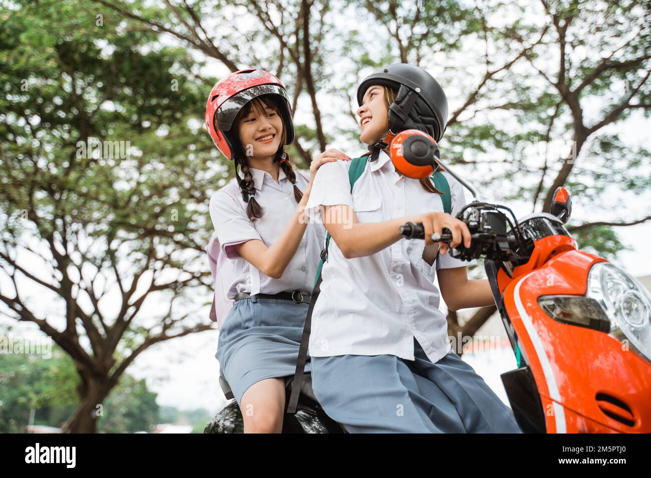 Two girls chatting while riding a motorcycle together Stock Photo