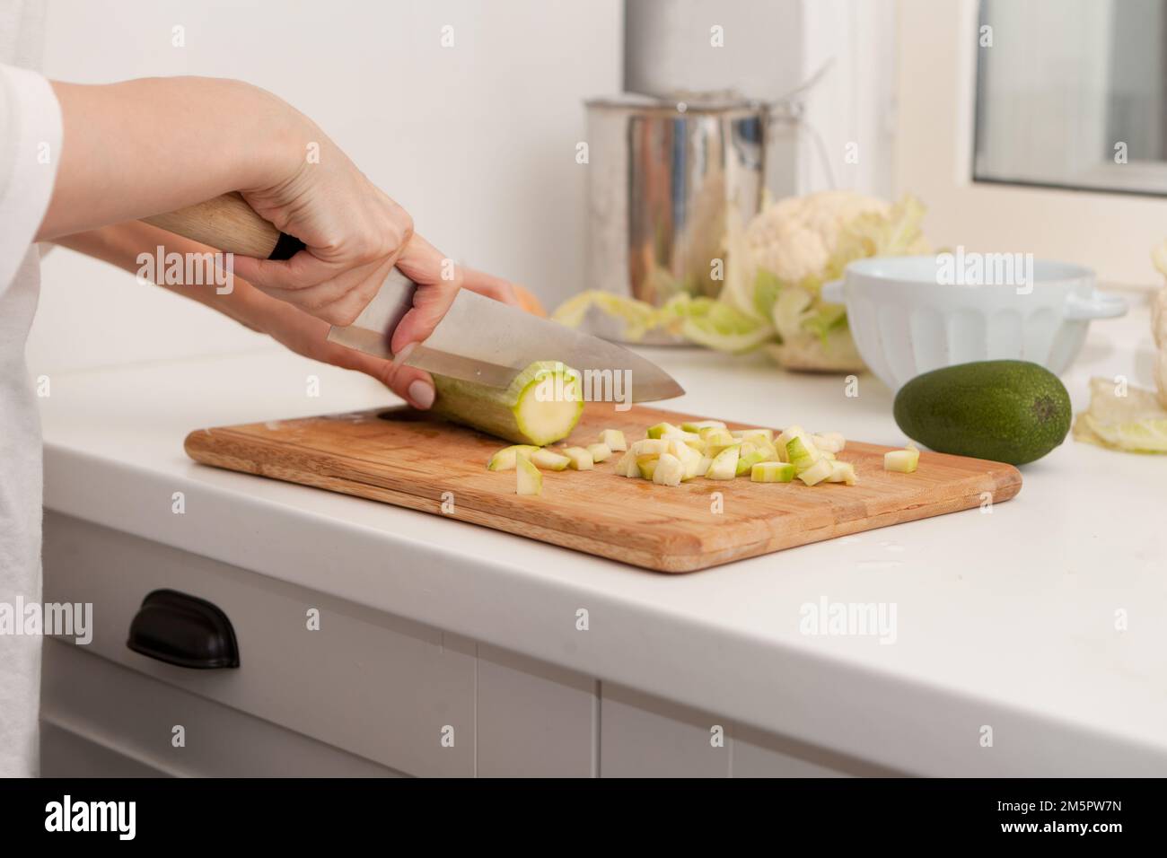 woman hands cutting vegetables at kitchen. Healthy and easy food. Close-up sliced vegetable marrow Stock Photo