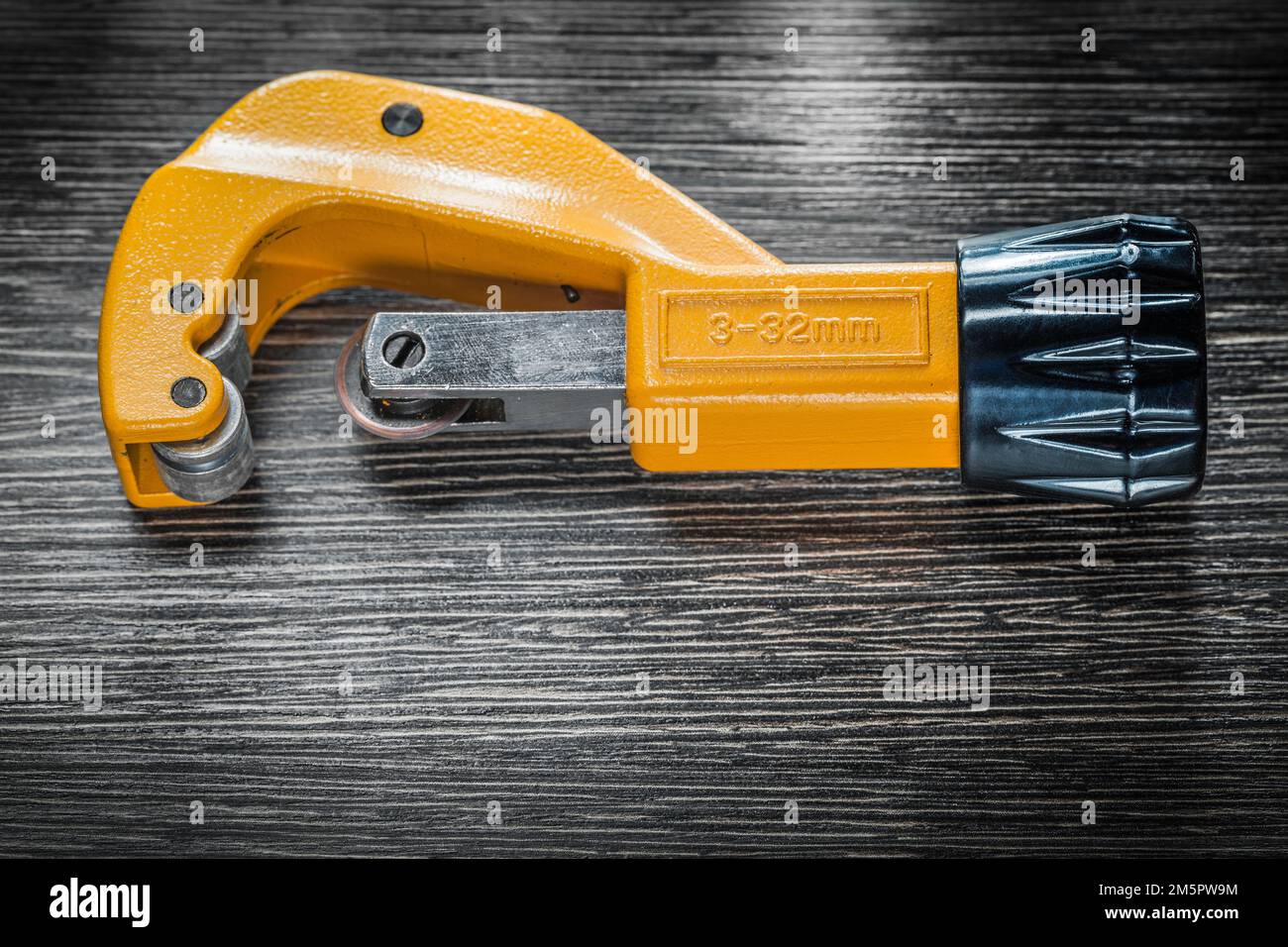 Plumbing pipe cutter on wooden board. Stock Photo