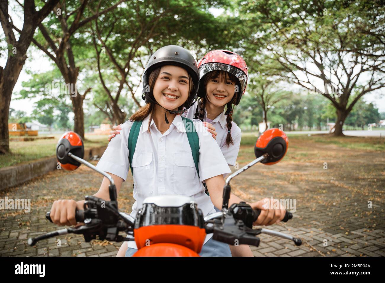 The joy of two asian student girls wearing helmets Stock Photo