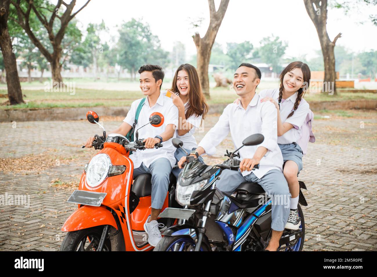 Group of high school students riding a motorcycle without helmet Stock Photo