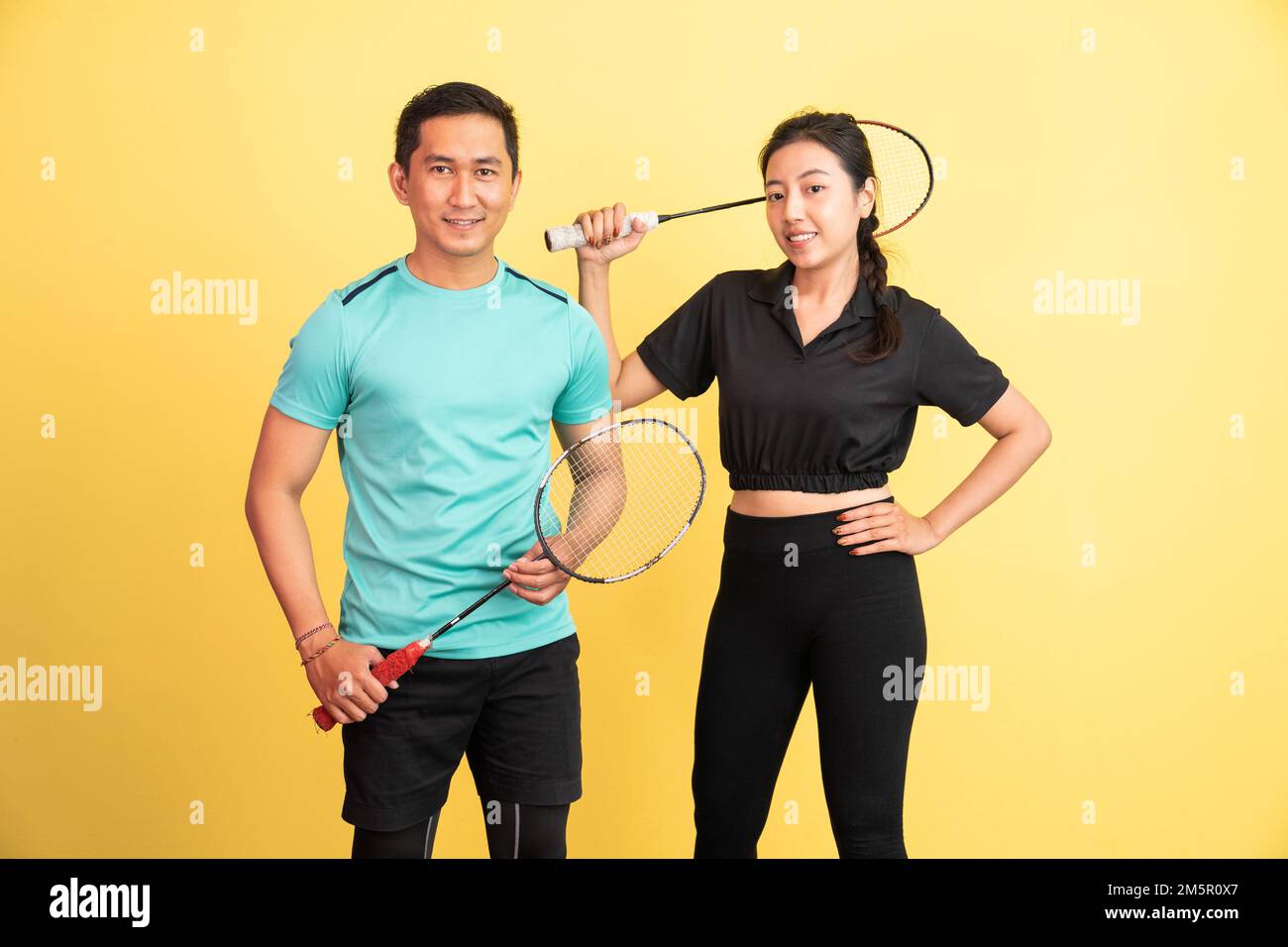 smiling asian woman and man standing holding racket Stock Photo