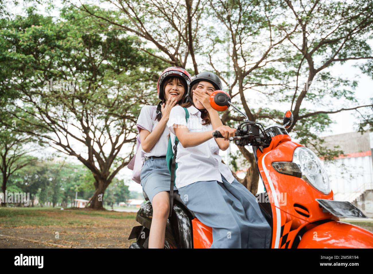 Two student girls wearing helmets laughing happily Stock Photo