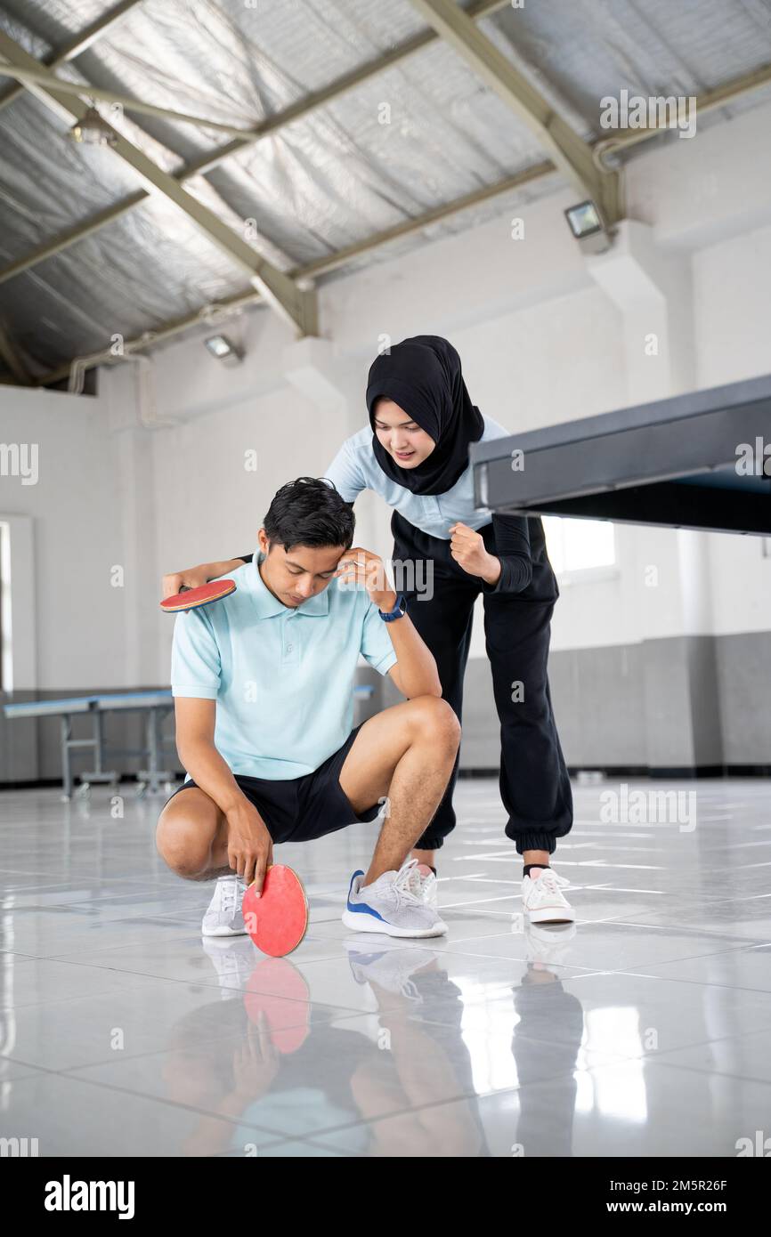 female athlete in hijab encouraging male partner disappointed Stock Photo