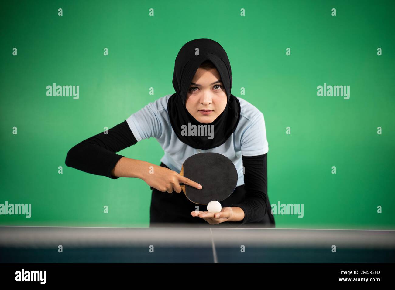 female athlete in hijab preparing to serve Stock Photo