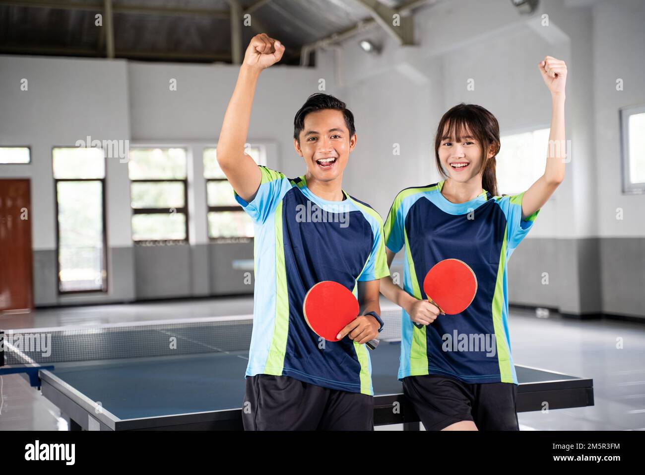 Two ping pong players holding paddles with raised fists Stock Photo Alamy