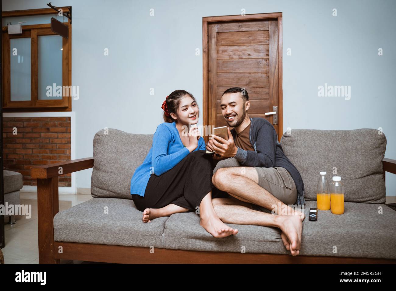 young asian woman and man chatting while using smartphones together Stock Photo