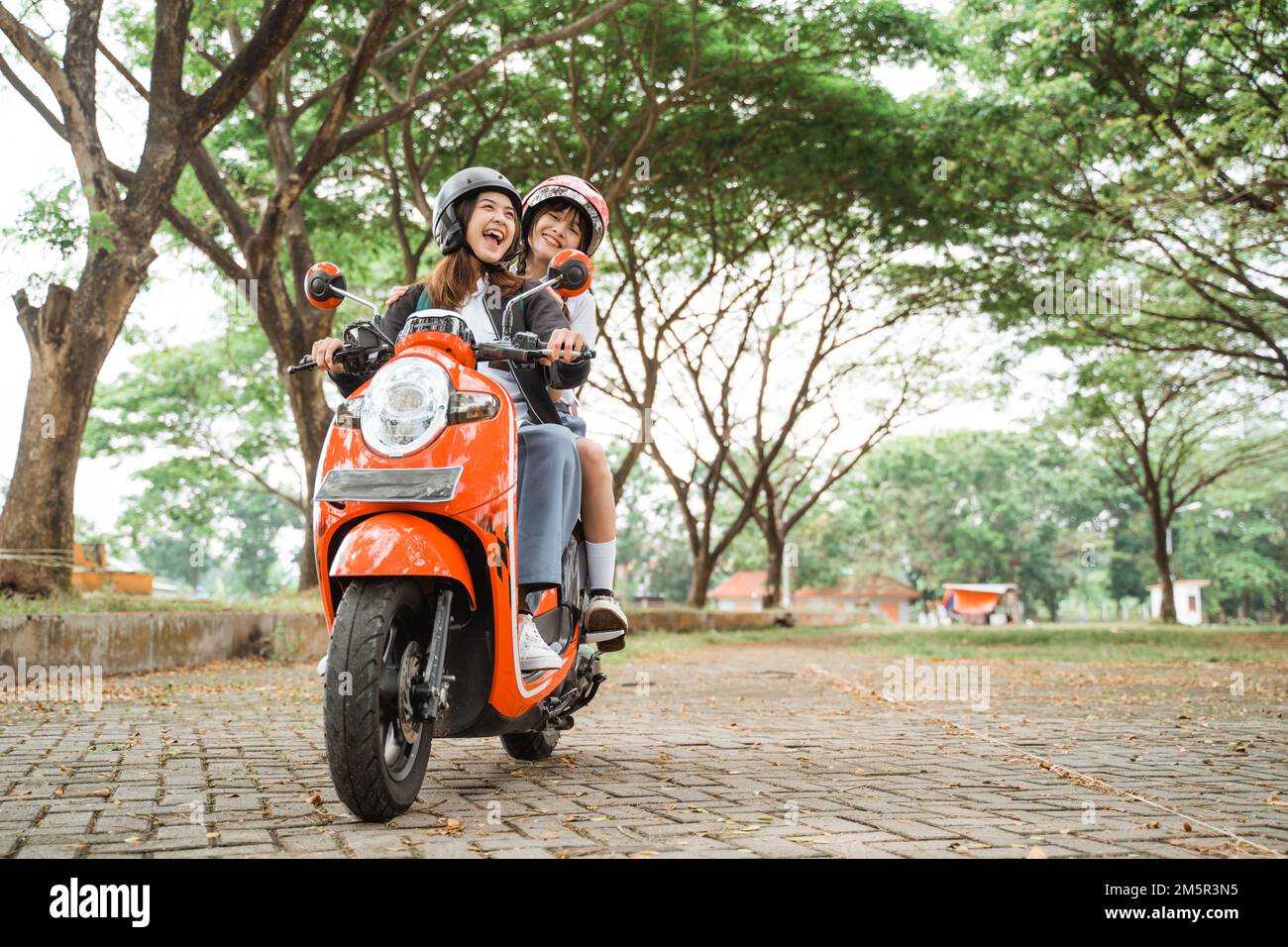 Two happy friends chatting riding a motorcycle Stock Photo
