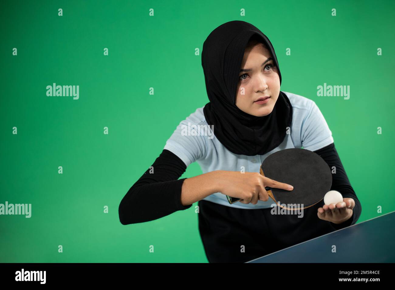Asian Muslim female athlete preparing to serve Stock Photo