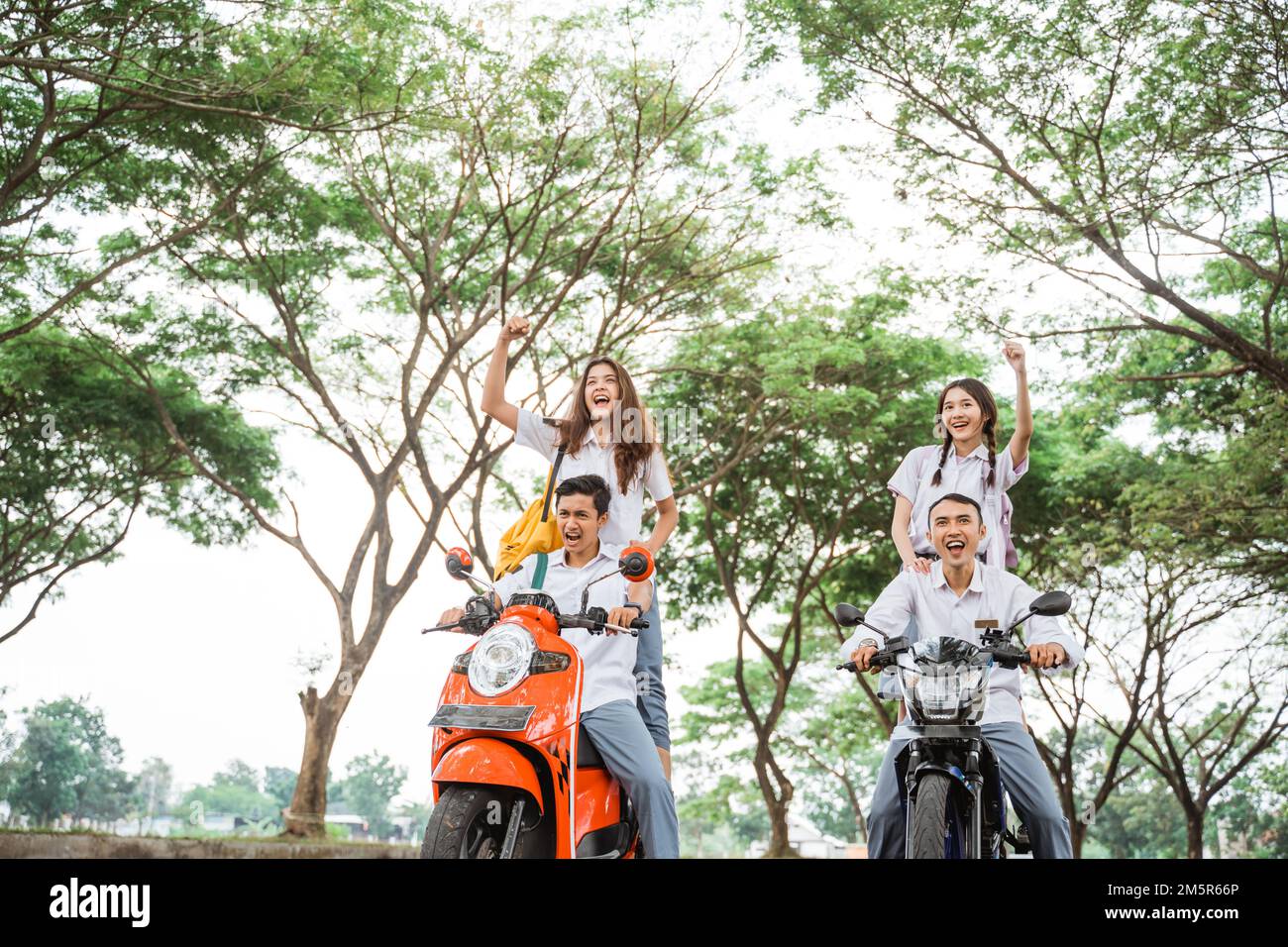 Two pairs of high school students riding reckless motorbikes Stock Photo