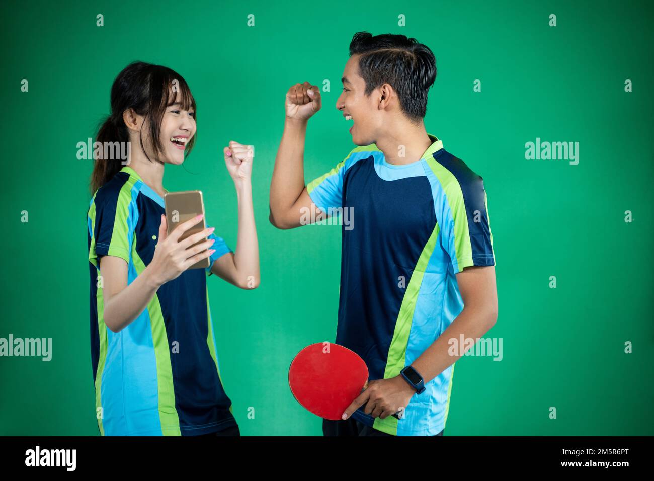 female and male athletes looking at smartphones with clenched fists Stock Photo