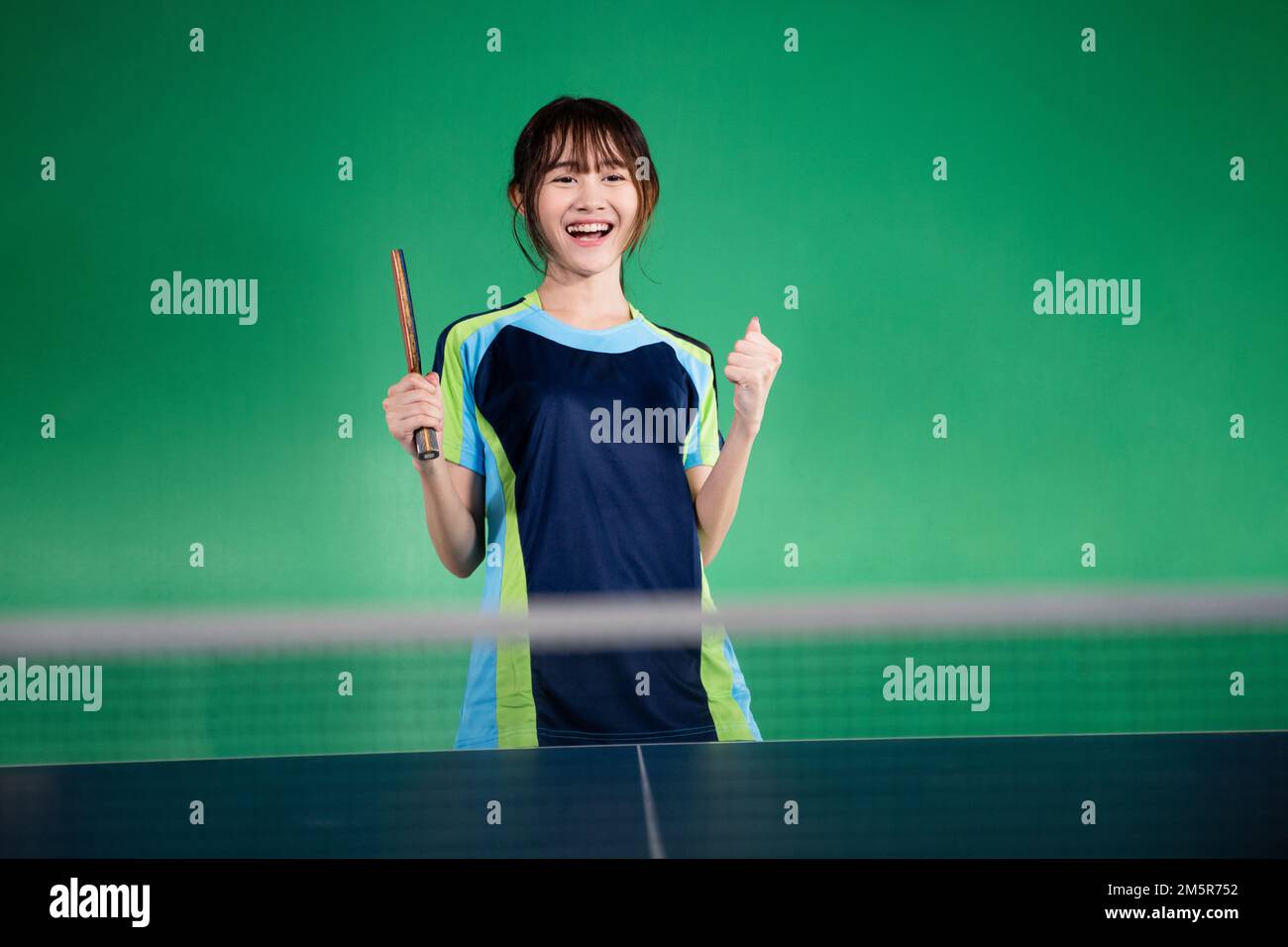 Asian female player with fist while winning ping pong match Stock Photo