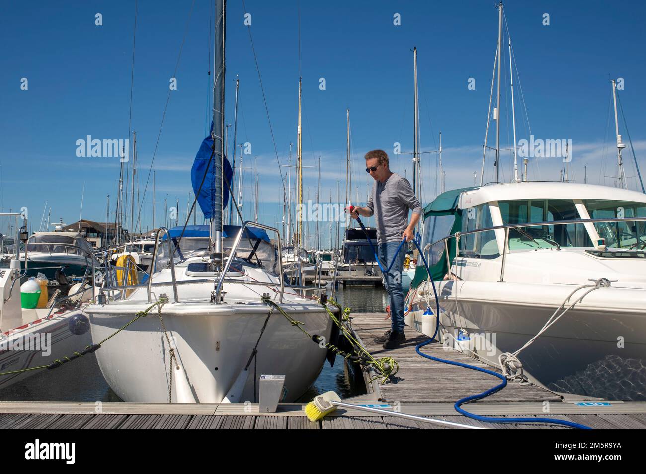 Man washing and cleaning his sailing yacht in a marina, boat maintenance Stock Photo Alamy