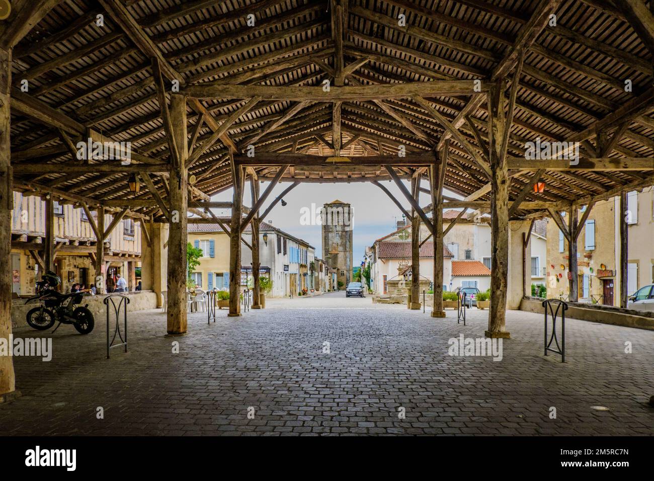 View on the main street and the medieval dungeon from the wooden covered market hall of Bassoues (South of France, Gers) Stock Photo