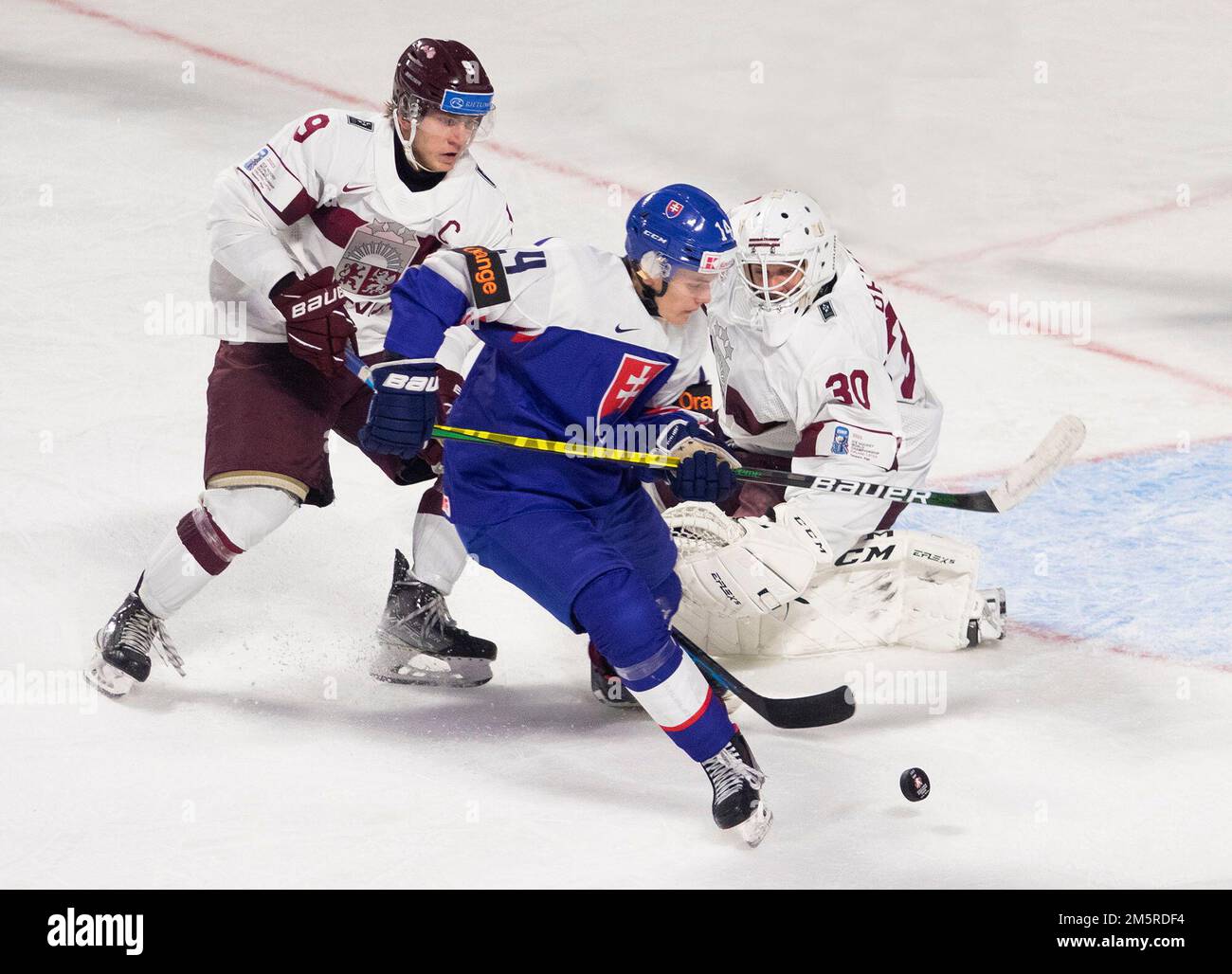 December 30, 2022, Moncton, NB, Canada Slovakias Simon Nemec (centre) splits Latvias Rainers Rullers (left) and Roberts Cjunskis during first period IIHF World Junior Hockey Championship hockey action in Moncton, N.B., on