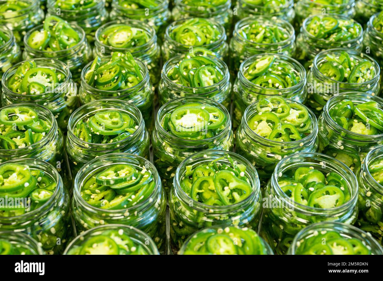Fresh jalapeno peppers in jars close up. Preparation for conservation. Homemade canned vegetables. Healthy fermented food. Top view. Stock Photo
