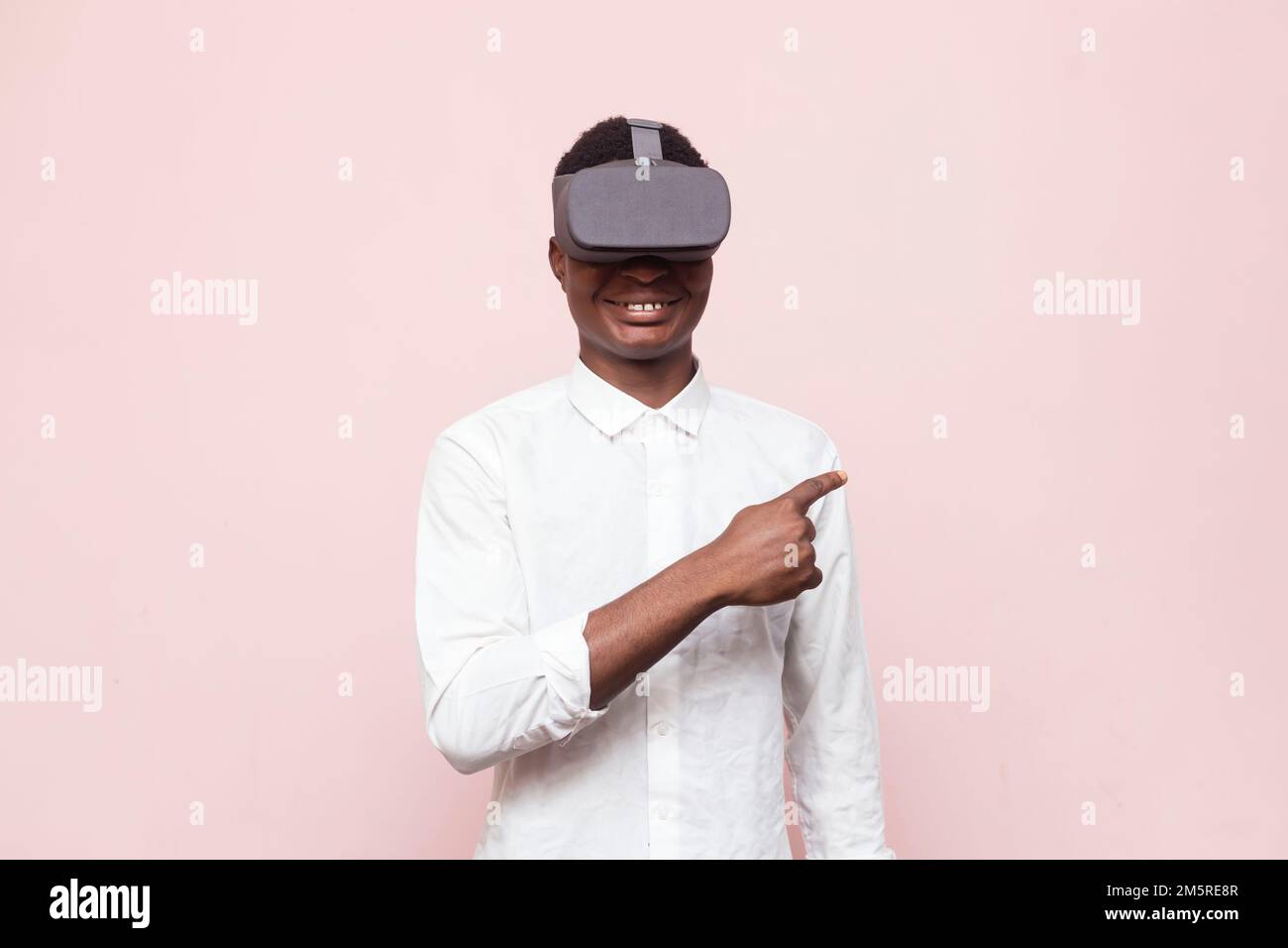 An excited African gamer wearing VR googles, simulated 3D environment isolated on pink background Stock Photo