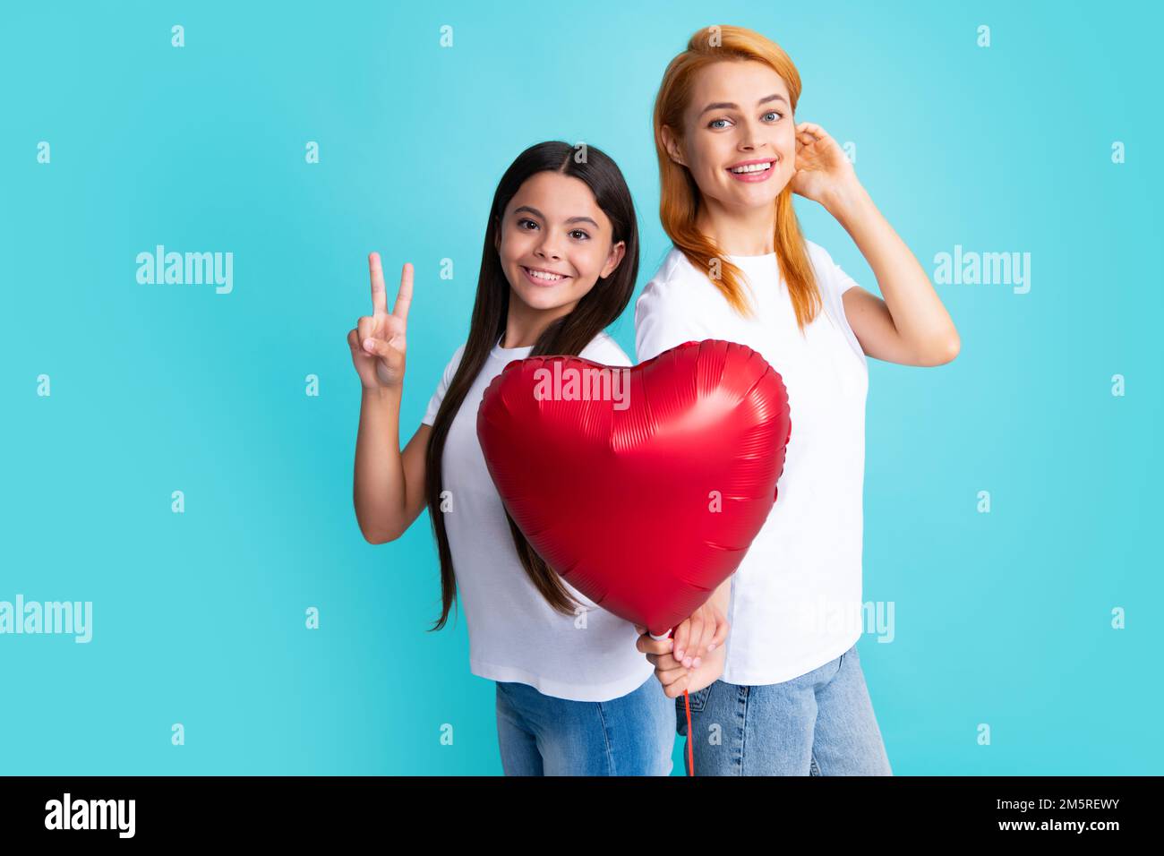 Valentines day. Smiling mother and daughter holding love heart balloon on blue background. Happy Valentines day to my mom. Stock Photo