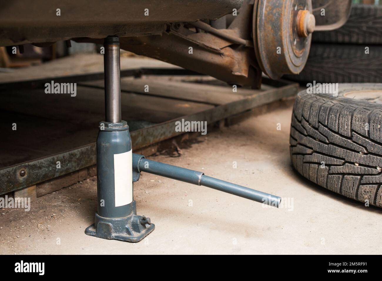 Car on tire mounting with removed wheel on pneumatic jack Stock Photo