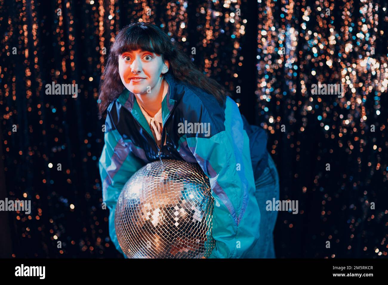 Young sporty woman 80 and 90's style. 90s fashion positive girl at night club disco party with disco ball Stock Photo