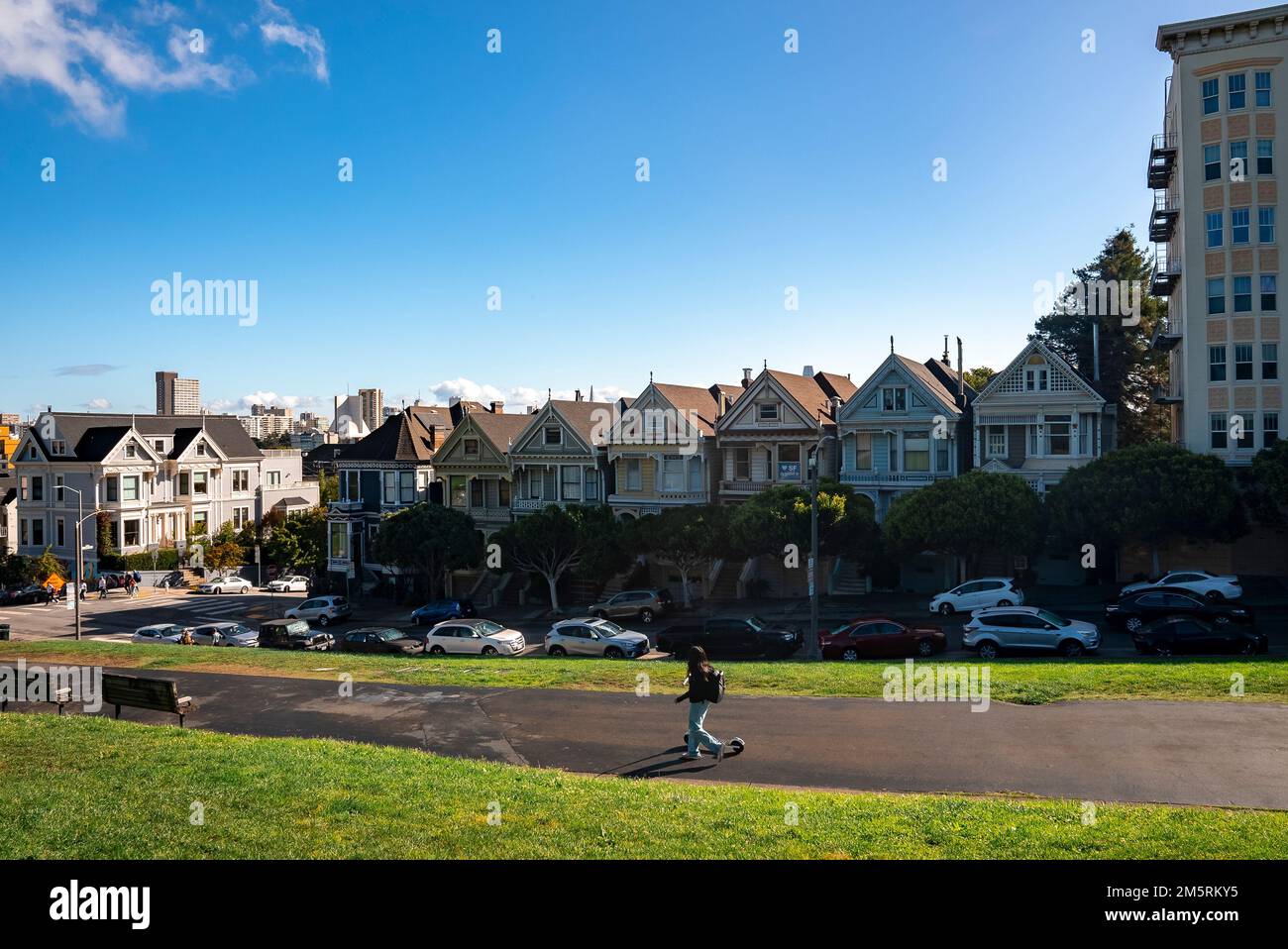 Woman walking on road in front of Painted Ladies Houses at Alamo Square Stock Photo