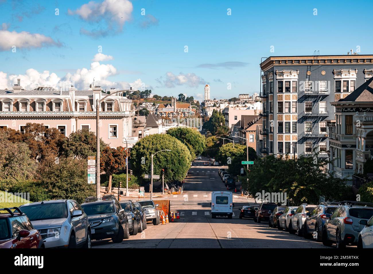 Cars parked on street amidst painted ladies buildings at Alamo Square Stock Photo