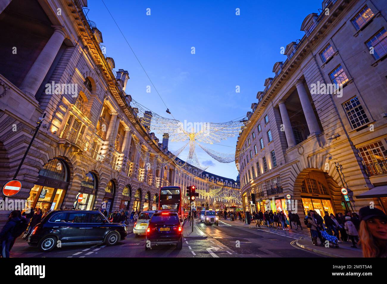 People and traffic along Regent Street in London, UK. Evening view of Regent Street with Christmas lights above the road Stock Photo