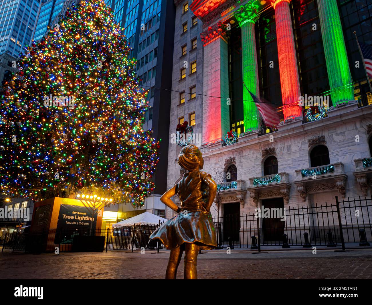 'The Fearless Girl' looking at New York Stock Exchange at Christmas. View from Broad Street, Manhattan, New York, USA Stock Photo