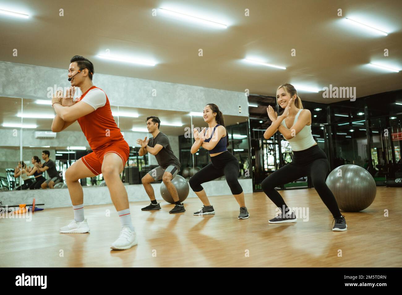 male instructor doing squats and hand defense with participants Stock Photo