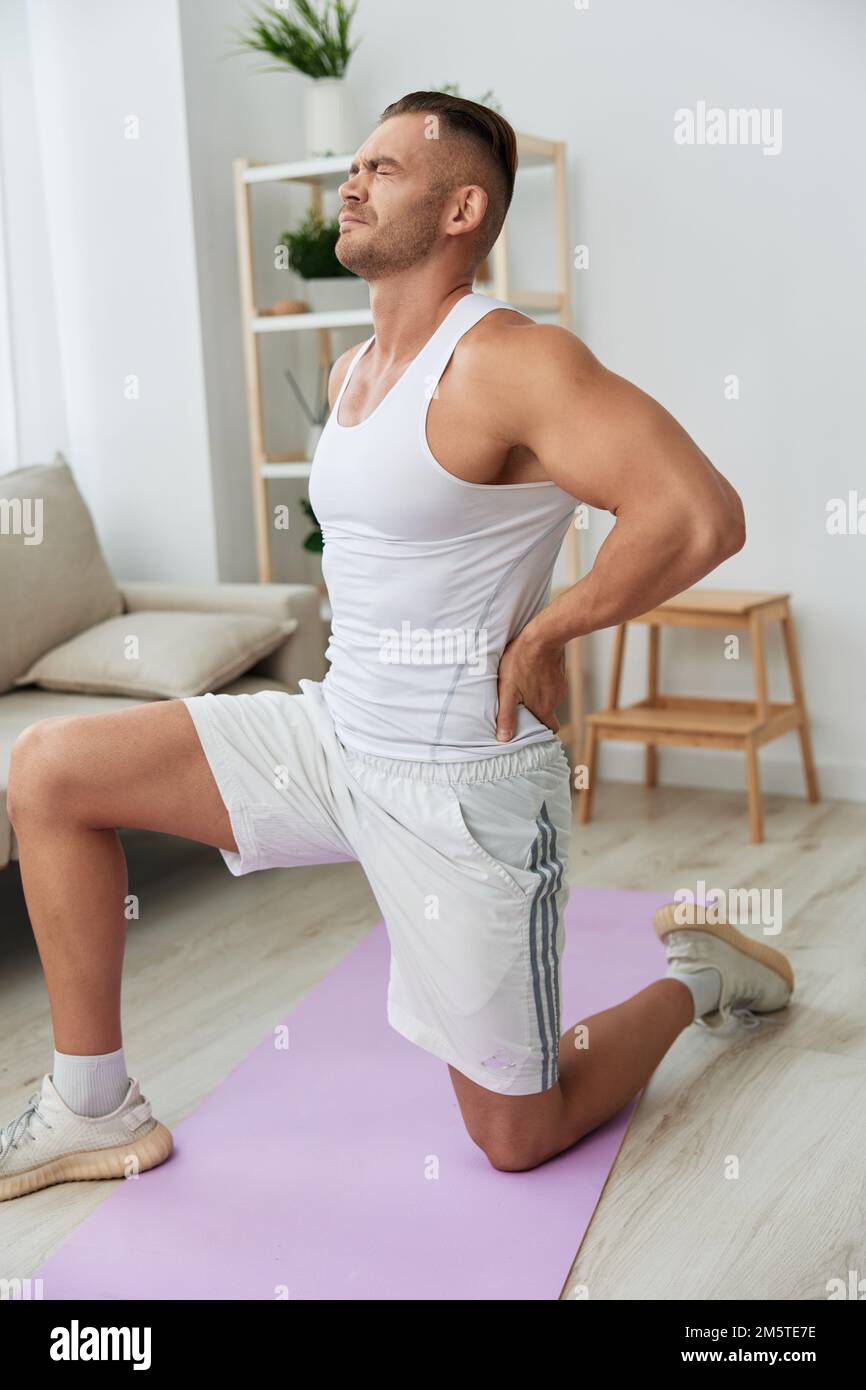 Man sports back pain after working out at home, pumped up man works out