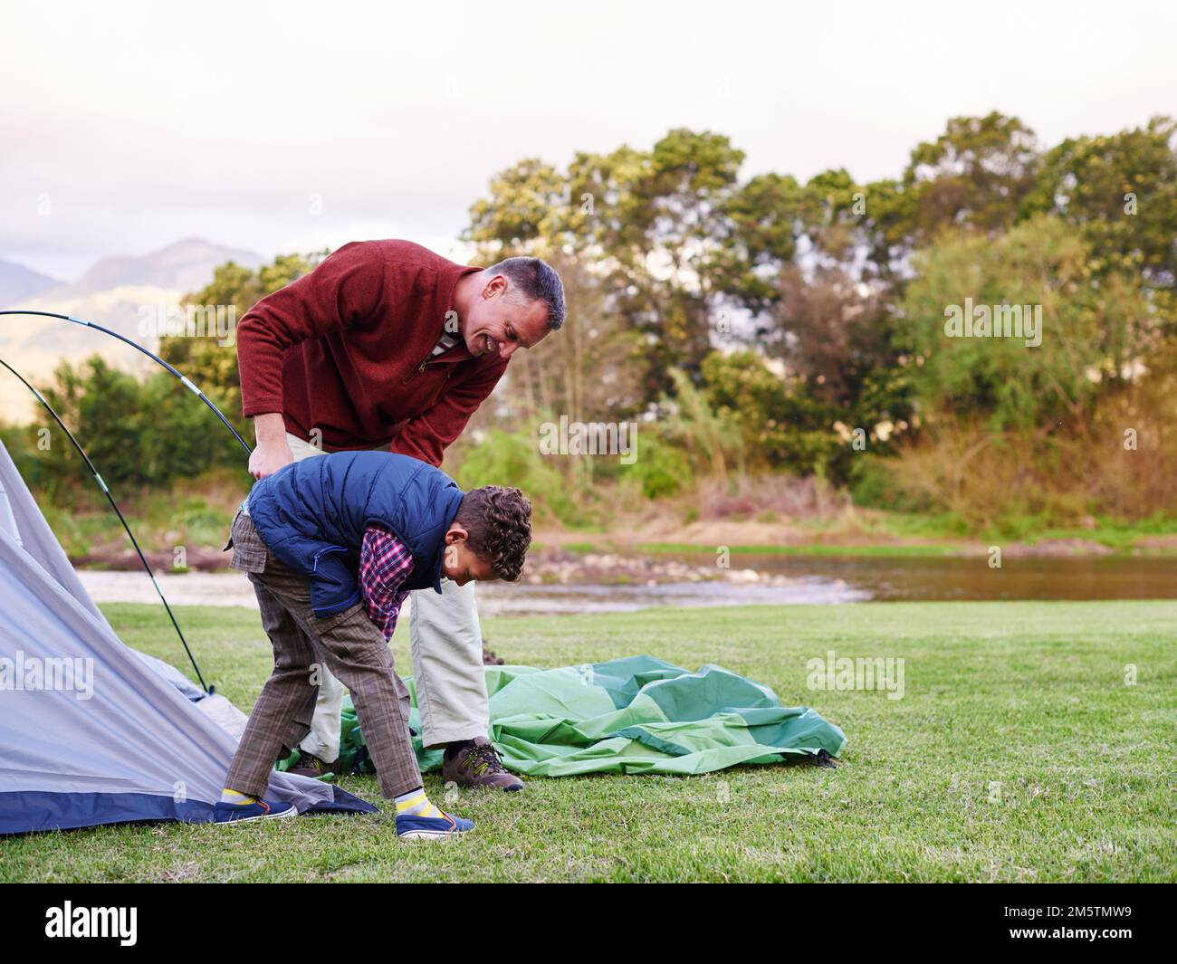 There you go. a father and son setting up a tent together while camping